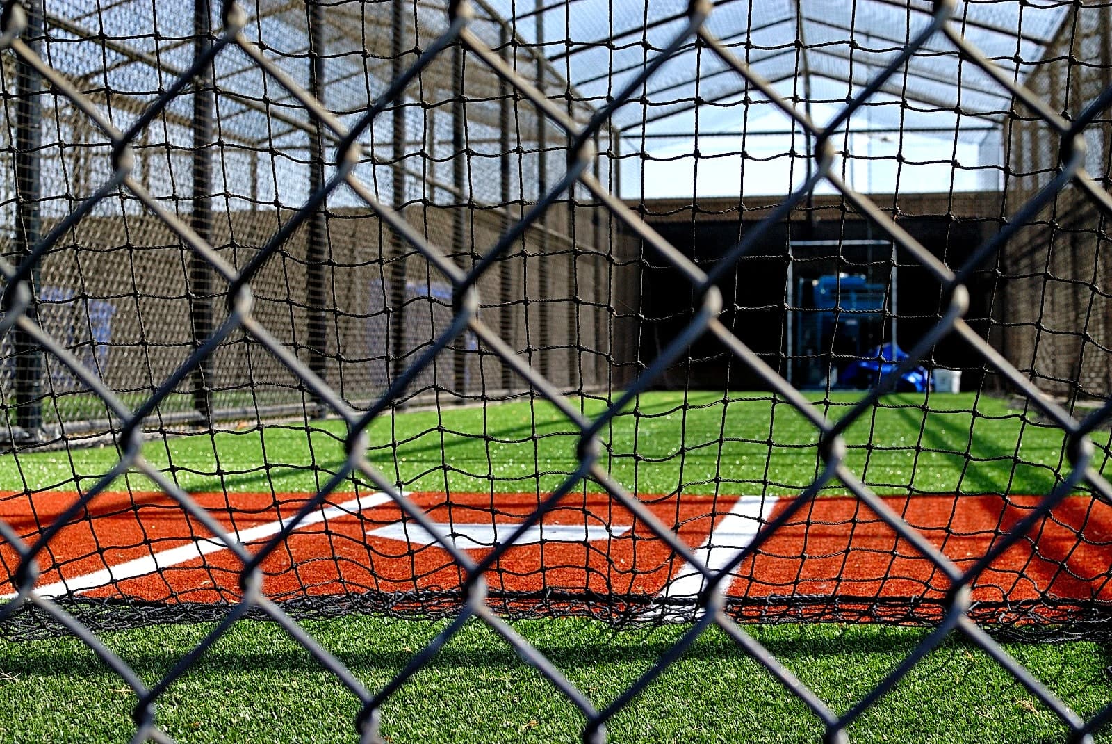 Youth baseball team practicing in a batting cage at night
