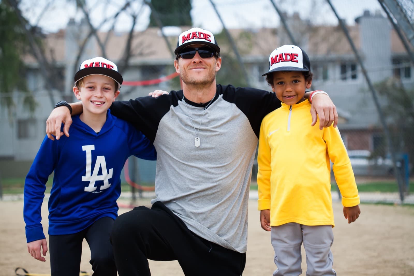 Isaac with two young players after a session, all three in MADE Baseball caps