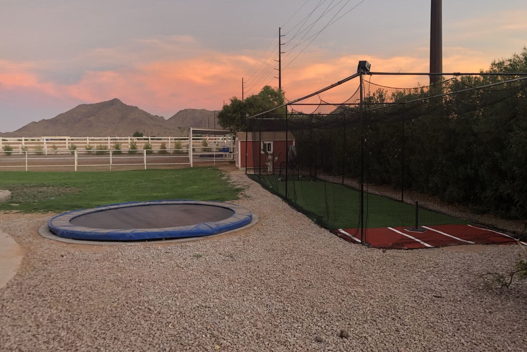 A finished backyard batting cage at sunset