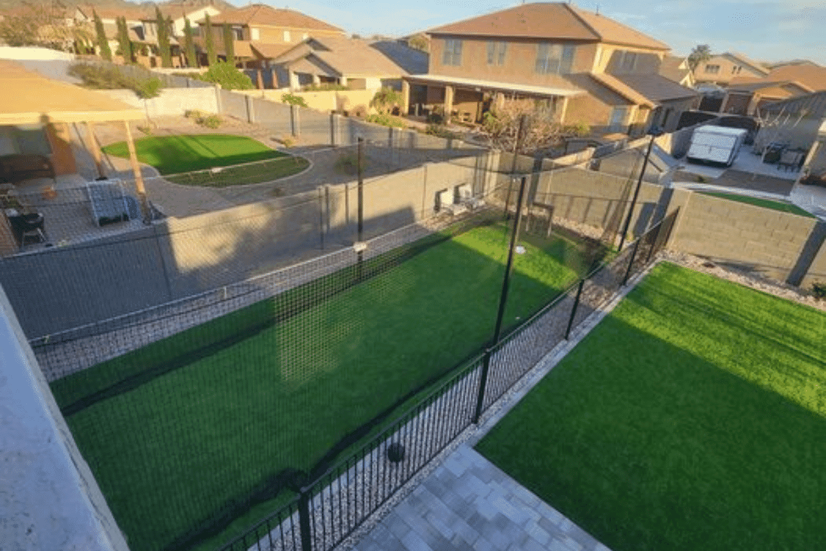 A backyard batting cage with neighbors' rooflines directly above it
