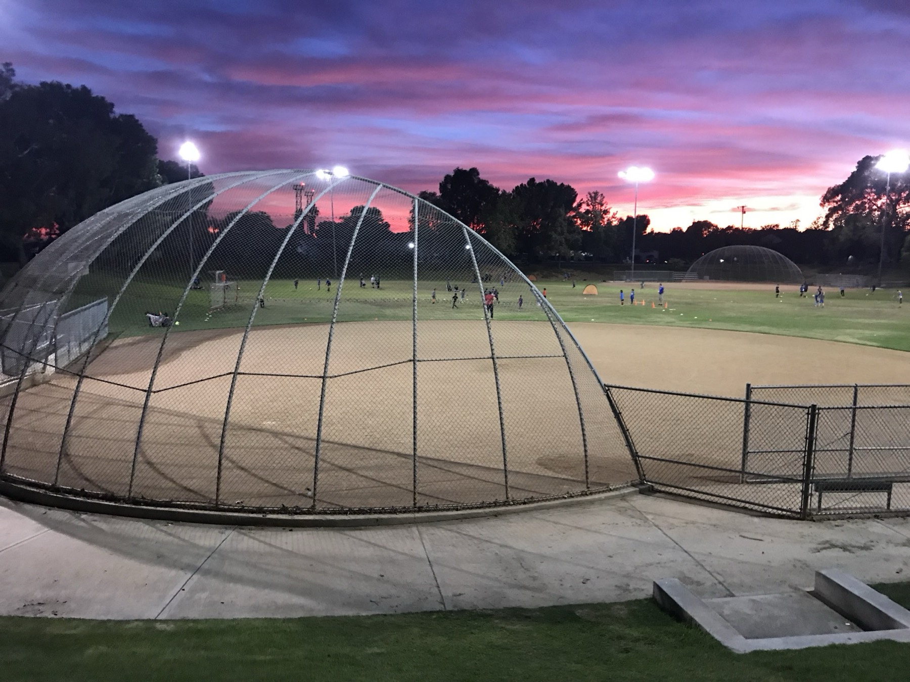 A youth baseball field and batting dome at sunset